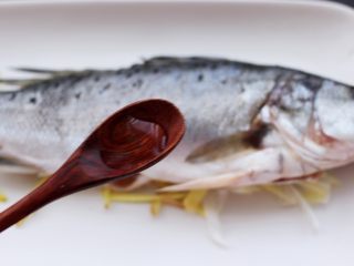鲜美无比的粤式清蒸鲈鱼,这个时候在鱼身上浇上料酒来去除鱼的腥味。