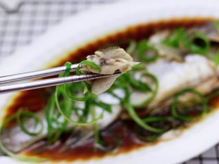 鲜美无比的粤式清蒸鲈鱼,享用鲈鱼之前用勺子把盘子里的鱼汤舀起来淋到鲈鱼身上。