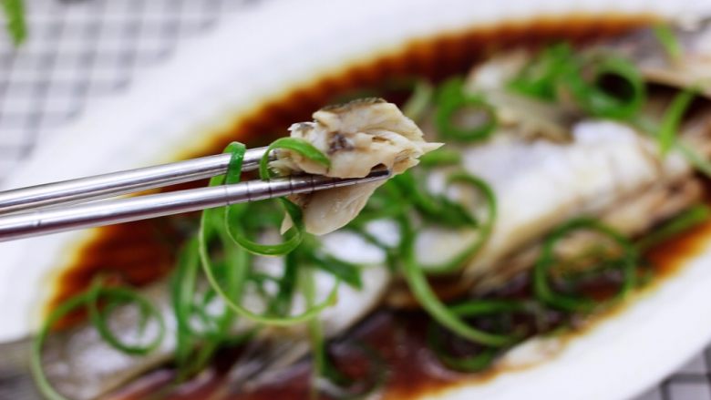 鲜美无比的粤式清蒸鲈鱼,享用鲈鱼之前用勺子把盘子里的鱼汤舀起来淋到鲈鱼身上。