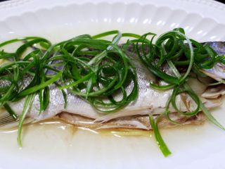 鲜美无比的粤式清蒸鲈鱼,把浸泡好的葱丝码放在蒸好的鲈鱼身上。