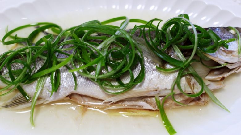 鲜美无比的粤式清蒸鲈鱼,把浸泡好的葱丝码放在蒸好的鲈鱼身上。