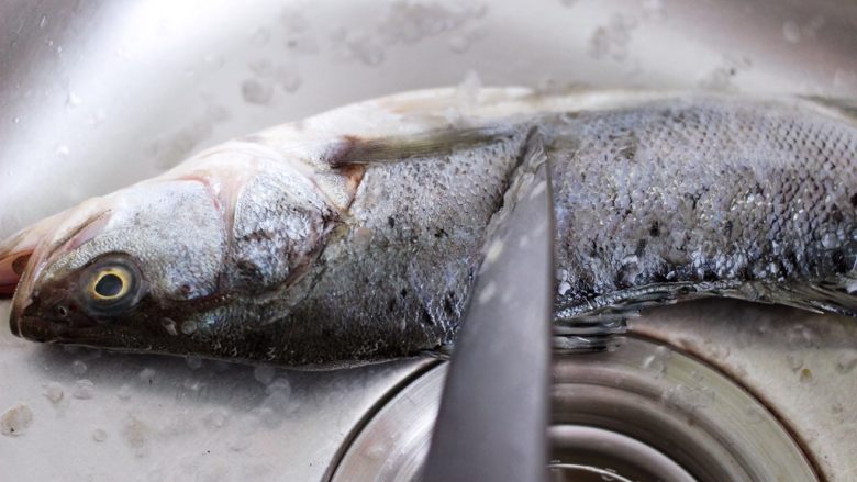 鲜美无比的粤式清蒸鲈鱼,把鲈鱼放到水池里后，用刀去鳞，如果鱼鳞不除会影响口感。