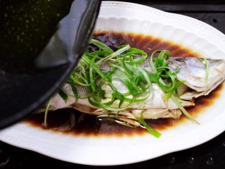 鲜美无比的粤式清蒸鲈鱼,锅中烧热花生油后，直接从头到尾浇到鲈鱼身上。