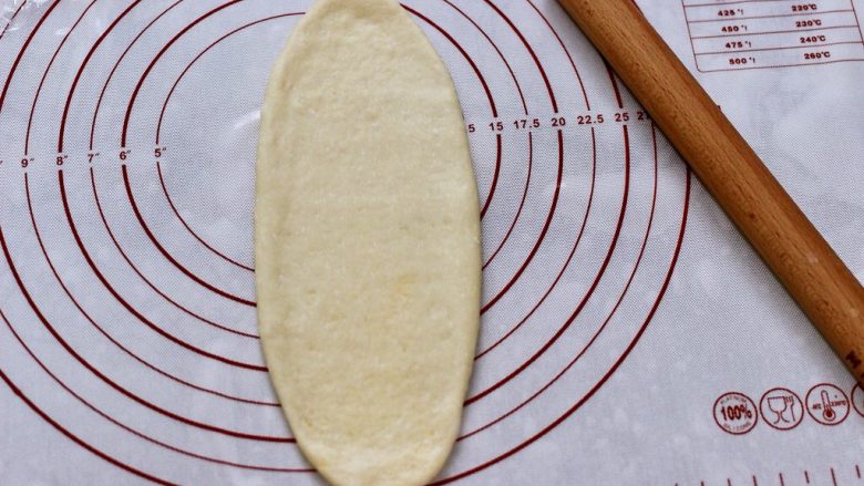 椰蓉奶香面包圈,慢慢用擀面杖擀成稍长些的椭圆形。