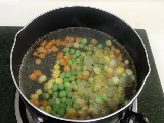 馒头蔬菜什锦沙拉,锅内加入适量清水煮沸，然后把玉米粒、胡萝卜粒和豌豆一起放入煮熟。
