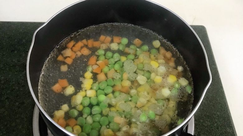 馒头蔬菜什锦沙拉,锅内加入适量清水煮沸，然后把玉米粒、胡萝卜粒和<a style='color:red;display:inline-block;' href='/shicai/ 148'>豌豆</a>一起放入煮熟。