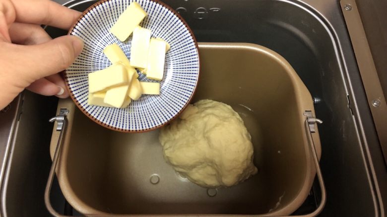 超简易吐司,将室温软化的黄油切小块放入面包机中继续揉面25分钟