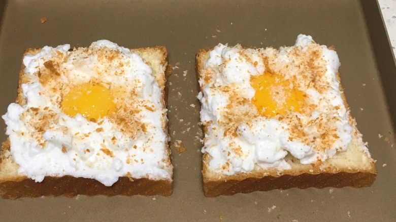 快速早餐吐司片-鸡蛋味,蛋白霜挑入吐司片上，中间留出空间，放入蛋黄，表面撒少许细砂糖，再放一些切吐司片出来的碎隙。