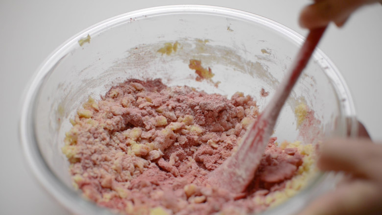 草莓杏仁饼干球,分2次加入草莓粉和面粉，用刮刀混合均匀。