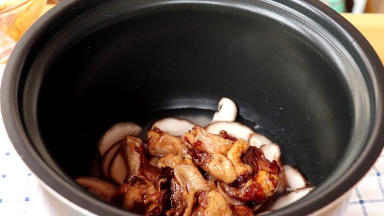 电饭锅焖饭,铺一层香菇，上面放上腌制好的鸡翅根