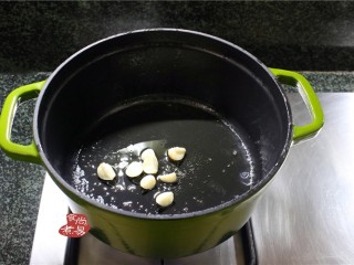 私房一品煲仔菜,烧热珐琅锅，倒入食用油，将蒜头爆出香味。
