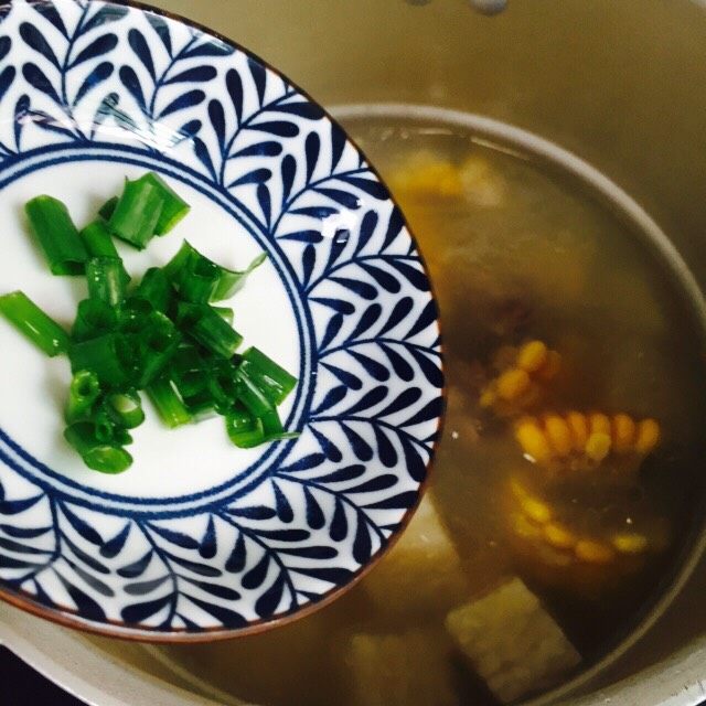 小寒养生汤+糯米山药玉米筒骨汤,放入适量的葱花搅拌均匀