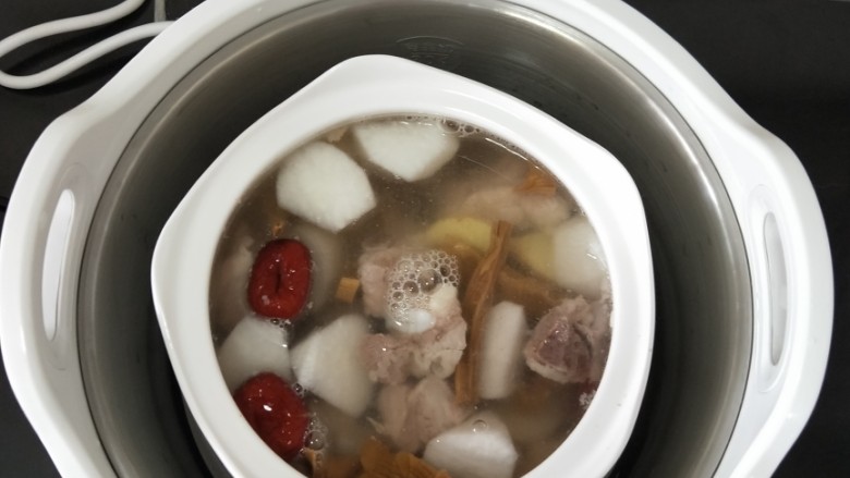 干笋萝卜排骨汤,拿出九阳桃花盏电炖锅，放入蒸格，再加入清水至水位线。把炖盅放到蒸格中间位置。