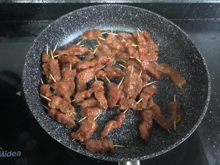 孜然牙签牛肉,倒入牙签肉，不要急着翻炒，等到闻到肉香，底部肉估计变颜色以后再翻炒。