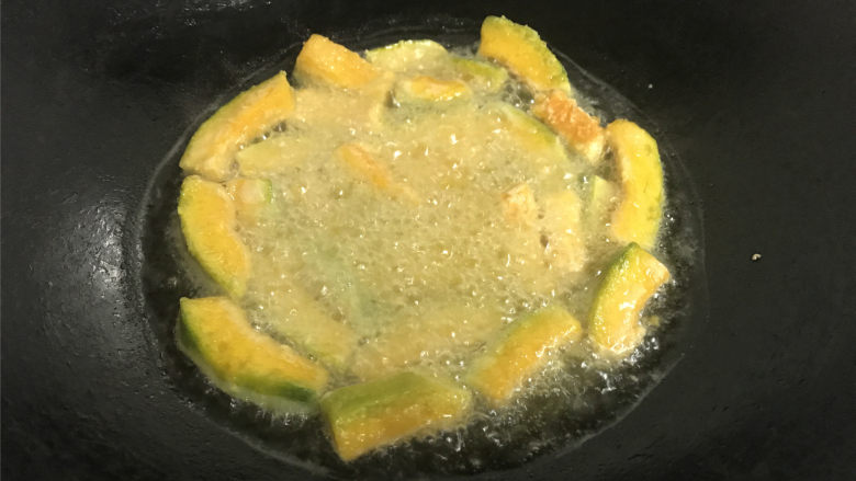 咸蛋黄焗南瓜,锅中倒入适量的油，把裹上淀粉的南瓜条放入锅中，炸至表面呈金黄色后捞出。