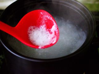 紫薯百合冰糖粥,大火煮沸后用勺子撇去沙锅里的浮末。