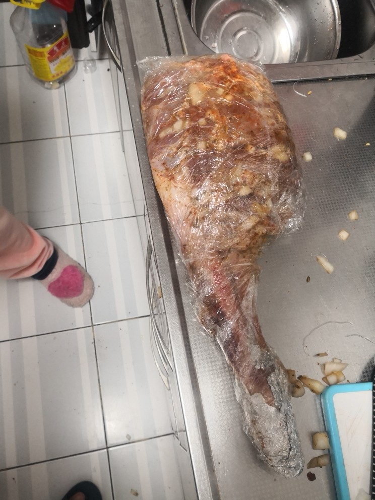 烤羊腿,用保鲜膜将上了料的羊腿包裹好，放入冰箱冷藏24小时。