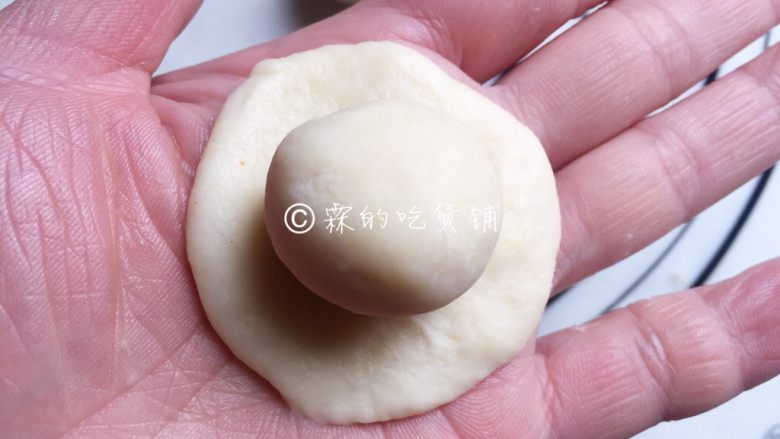 中式菊花酥,松弛好的水油皮面团按扁成圆形，将油酥团放在水油皮面团中