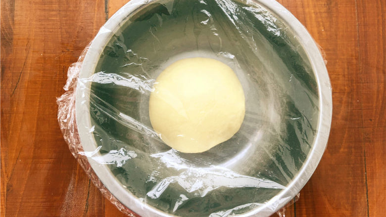 香葱肉松面包卷,揉至能轻松拉出手套膜，把面团重新整好，盖上保鲜膜，放置在温暖处发酵。

