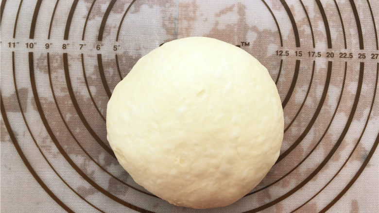 香葱肉松面包卷,发好的面团放到揉面垫上进行排气，排完之后盖上保鲜膜，醒15分钟左右。
