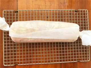 香葱肉松面包卷,趁着余热把面包卷起来，用油纸包裹之后拧紧两边固定一下，放凉以后再打开。

