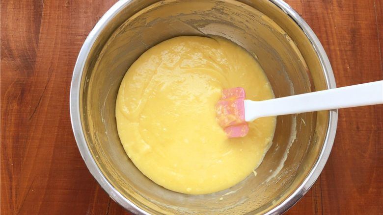 柠檬玛德琳甜甜圈,倒入面糊中。翻拌至黄油和面糊完全融合在一起。这个过程一定要有耐心。拌好的面糊可以放到阳台冷去一下（夏天就放冰箱）。用刮刀铲起面糊，面糊不会滴落即可。
