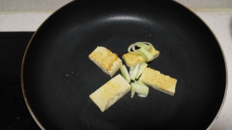 冻豆腐炒上海青,豆腐煎至两面金黄，放入葱碎。