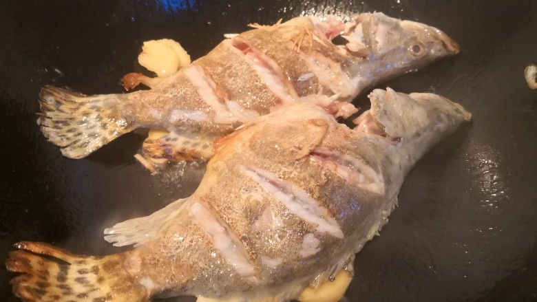 排骨鳜鱼粉皮煲,大火煎至用铲鱼可以滑动，然后将鱼翻身。放入姜片。