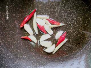 酸辣白菜,锅内放油，放入辣椒和蒜片翻炒爆香。