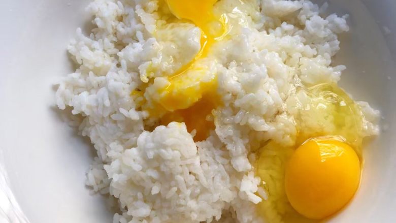 剩米饭新吃法,把剩饭放入大一点的碗里，戴上手套把剩饭捏散，再把鸡蛋打入，用筷子把鸡蛋和剩饭搅打均匀。