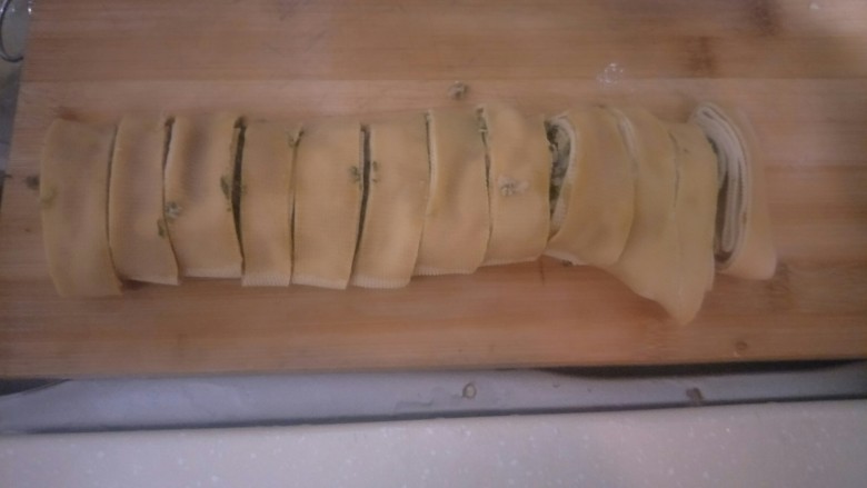 豆腐皮包荠菜肉末卷,放到砧板上。切段