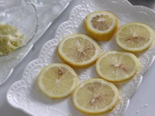柠檬蒸红虾，年夜饭食谱,柠檬片平铺到用来蒸制的盘子上。
