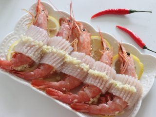 柠檬蒸红虾，年夜饭食谱,用切好的墨鱼条在虾的中间围一圈，撒一些蒜泥，也可以撒一些香草更有风味，或者小红绿辣椒点缀下。
