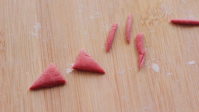 萌猪报春花样馒头,剩下的一块红色取少许面团，用刀切成两块三角形的形状，来做萌猪的耳朵。