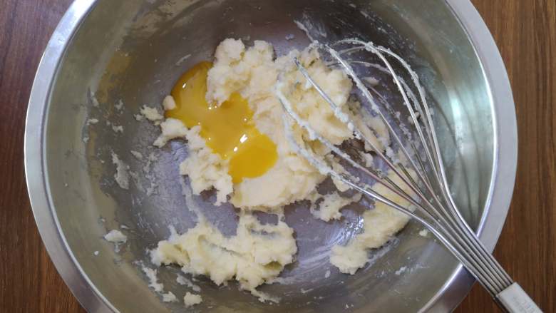 脆脆的奶香椰蓉球,将蛋黄分两次加入黄油中，并搅拌均匀。