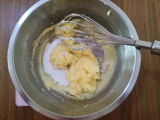 脆脆的奶香椰蓉球,牛奶也分两次加入黄油中，搅拌均匀。