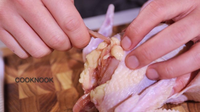 烤春鸡,小刀将连接鸡胸与肋骨的叉骨拆下， 鸡翅反折固定.