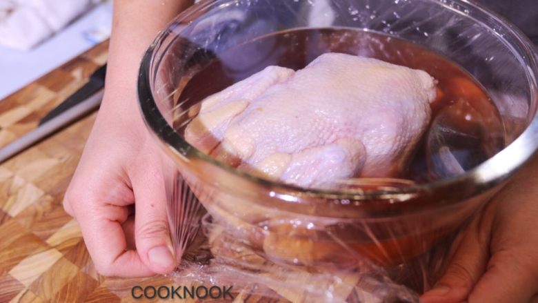 烤春鸡,把鸡浸入煮好的香料包水中, 保鲜膜包住