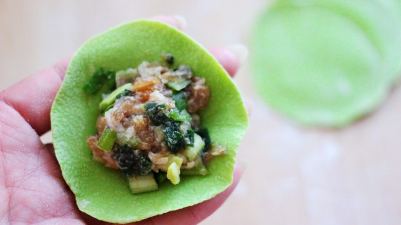 翠玉猪肉韭菜饺子,擀好的面皮里放入适量的馅料。
