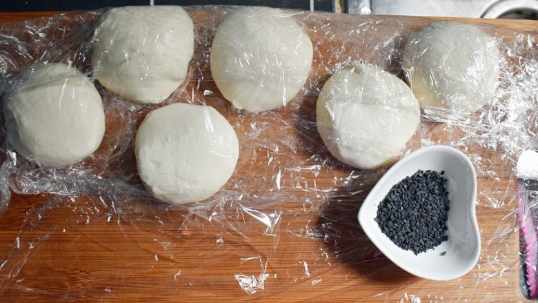 紫薯烧饼,将醒发好的面复揉成光滑的面团后，根据紫薯丸子的数量，将面团分成相同数量的面剂子，并准备适量的黑芝麻。