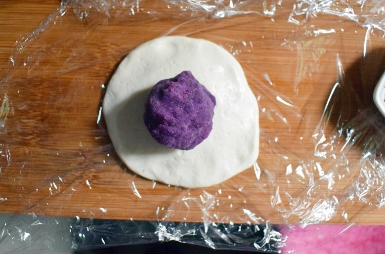 紫薯烧饼,去一个面剂子用手压成饼状，放上一个紫薯丸子。