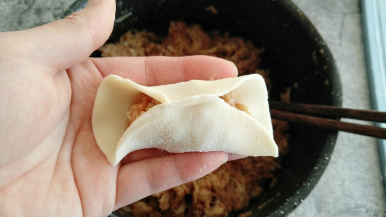 酸菜猪肉饺子,取一小部分饺子馅放饺子皮中间 饺子皮对折 从一端捏出褶子捏紧。