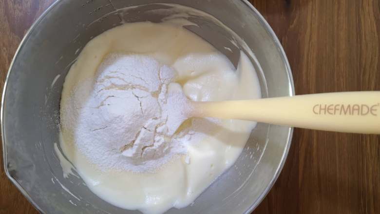 牛奶小蛋糕,将低筋面粉过筛，倒入蛋糊中，这一步一定要小心，搅拌时动作要轻，但每一次搅拌都要将一部分的干面粉与蛋糊混合好，最后搅拌至无干粉的状态。