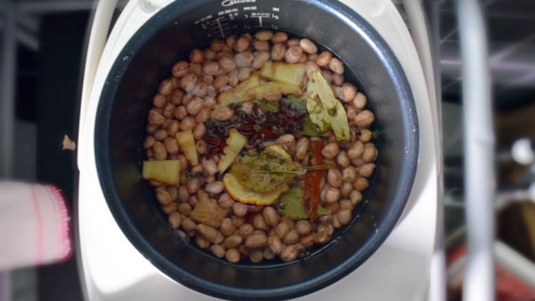 水煮花生米（电饭煲版）,将花生洗净放入电饭煲中，加入适量的水（一定要没过花生哦），并将调料和生姜倒入，浸泡半个小时。