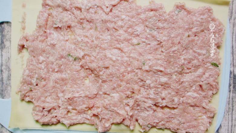 熏豆腐皮卷,把肉馅平铺在干豆腐皮上面，要均匀。