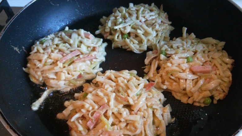 鸡蛋午餐肉面条煎饼,在扣在平底锅中。