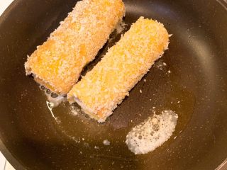 芝士火腿卷,冷锅热油，中小火放入面包卷煎至双面金黄出锅
