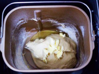 奶香四溢的紫薯小餐包,启动东菱面包机一个和面模式后，加入室温软化的黄油，再次启动面包机，一个和面程序10分钟。
