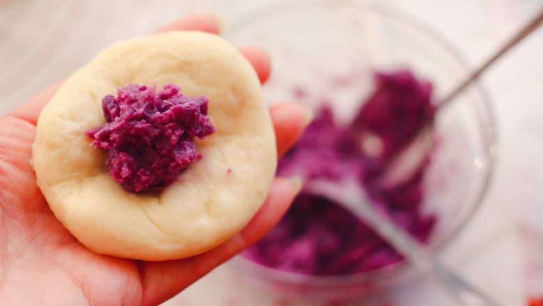 奶香四溢的紫薯小餐包,把静置松弛好的面团，用手摁扁后，加入适量的紫薯馅。