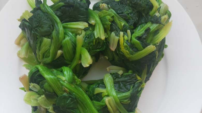 超级好吃又有营养的素炒菠菜 ,放凉的菠菜用手纂干里头的 水分，放入盘中备用。